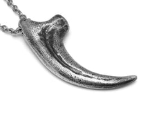 Antiqued Velociraptor claw necklace in pewter, shown from the side with stainless steel chain